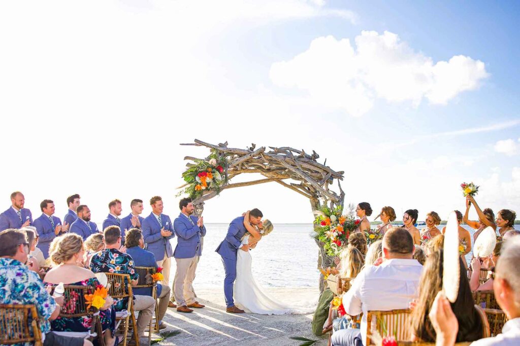 Beach wedding with guests, floral arch, and ocean backdrop at Largo Resort Key Largo
