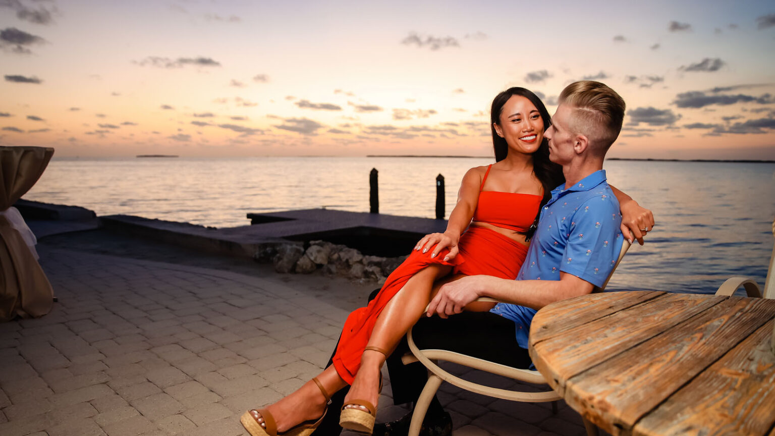 Romantic couple sitting together on an outdoor patio by the water at sunset at Largo Resort