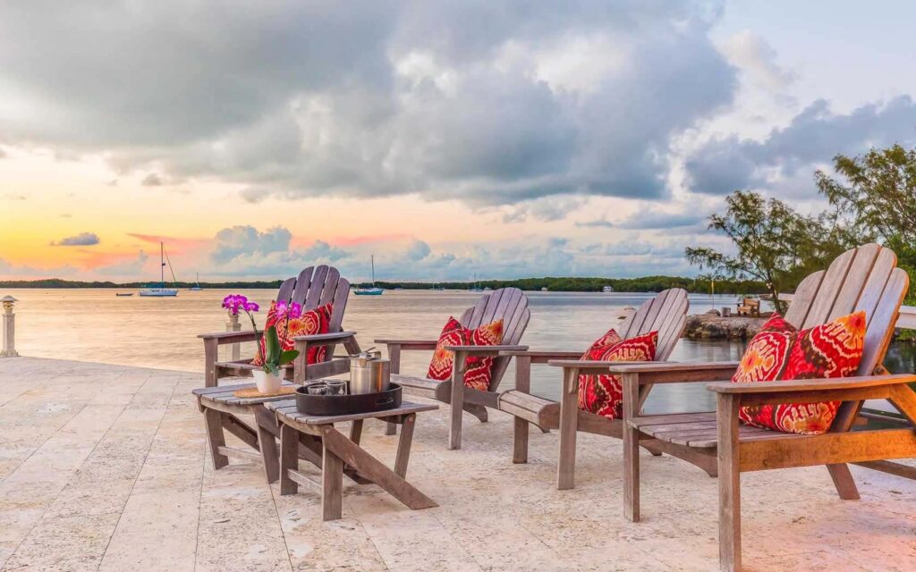 Wooden Adirondack chairs with throw pillows on the pier at sunset