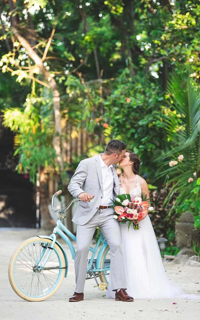 Bride and groom sharing a kiss on a beach cruiser bike at Largo Resort
