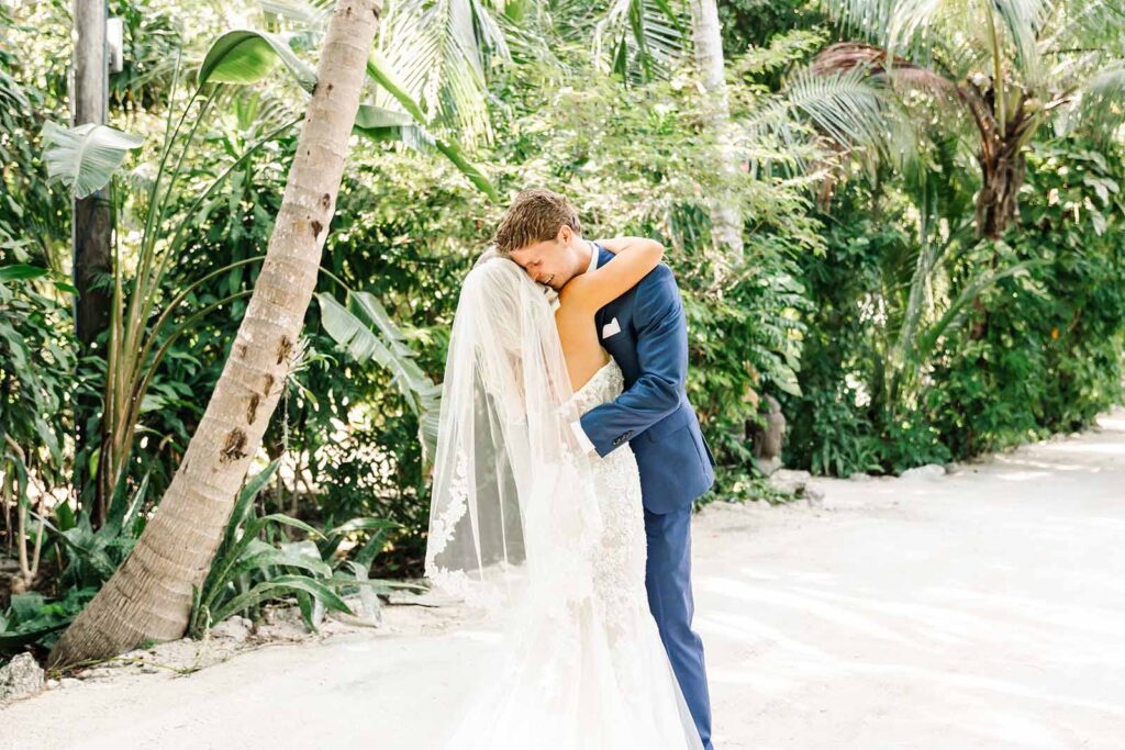 Happy bride and groom hugging on a path surrounded by tropical lush greenery at Largo Resort