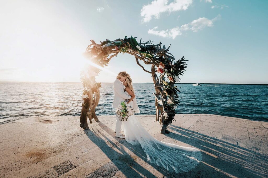 Romantic bride and groom embracing on the private waterfront at Largo Resort in Key Largo, Florida Keys – perfect Florida beachfront wedding moment with ocean views and tropical sunset backdrop