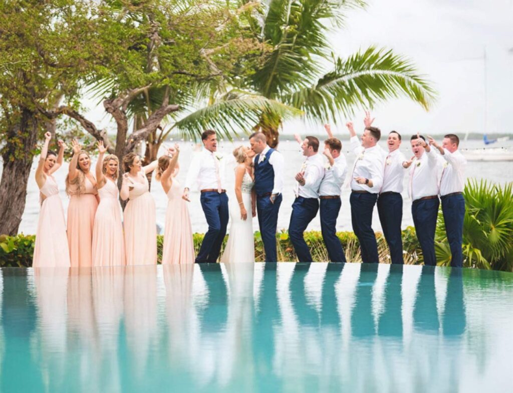 oyful Key Largo destination wedding at Largo Resort – happy couple kissing on infinity pool edge overlooking waterfront bay.